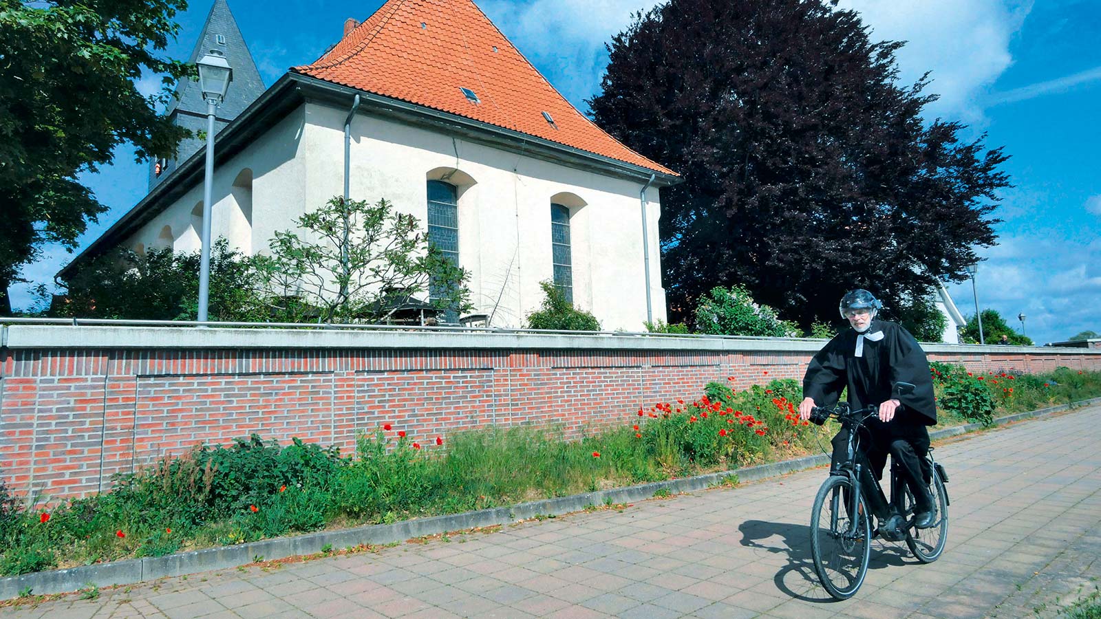 Pastor Jens Rohlfing mit seinem E-Bike vor der St.-Johannis-Kirche in Hitzacker. Der Pastor nutzt das Elektro-Fahrrad als Dienstfahrzeug, was die hannoversche Landeskirche finanziell fördert.