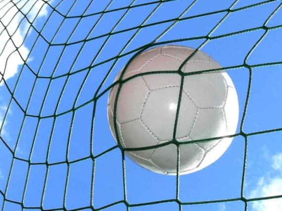 Fußball im Tornetz vor blauem Himmel