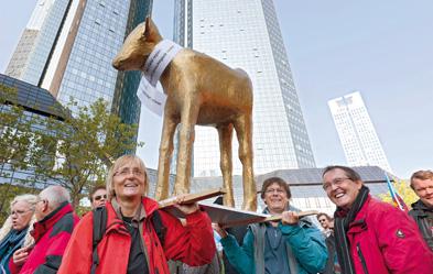 Biblisches Symbol: Demonstranten tragen ein goldenes Kalb durch Frankfurts Bankenviertel. Foto: epd/Stefan Trappe