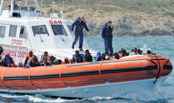Flüchtlinge und Küstenwache vor Lampedusa. Foto: dpa/Carlo Ferraro